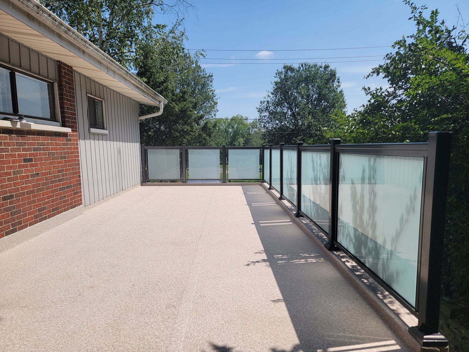 Custom modern aluminum glass railing ontario installation with heavy tempered panels on a backyard patio